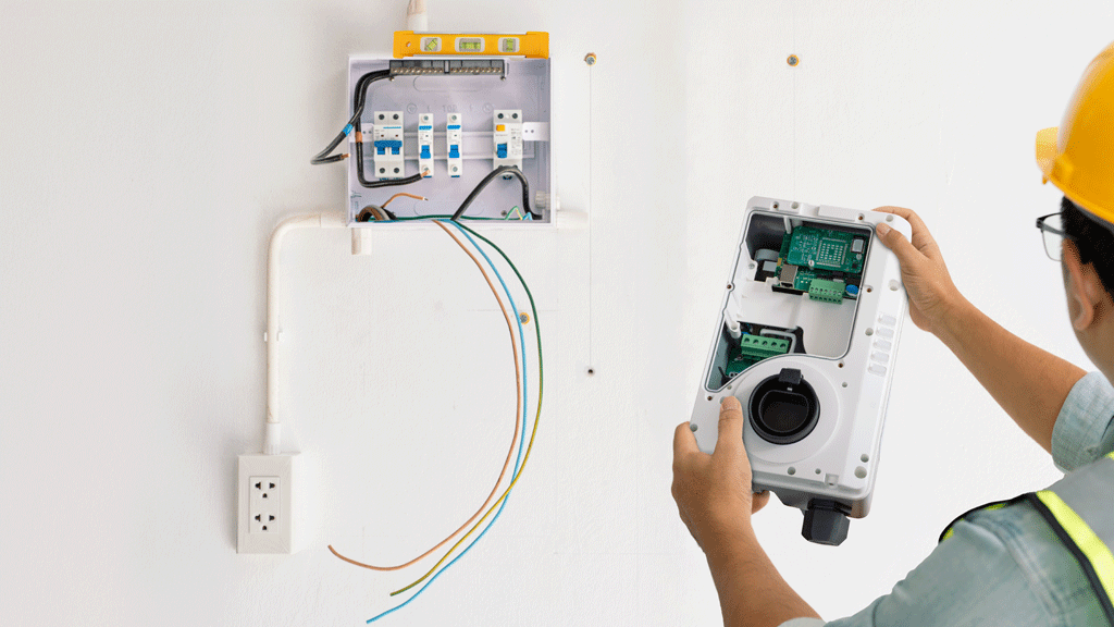 Électricien IRVE installant une borne de recharge dans un garage résidentiel